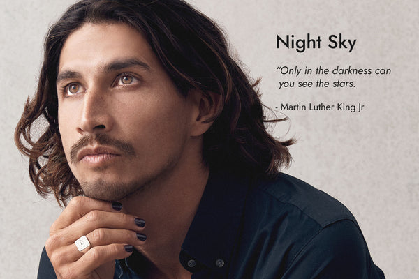 Man with tan skin tone and brown eyes wearing Stargazer navy blue nail polish, with Night Sky text and quote.