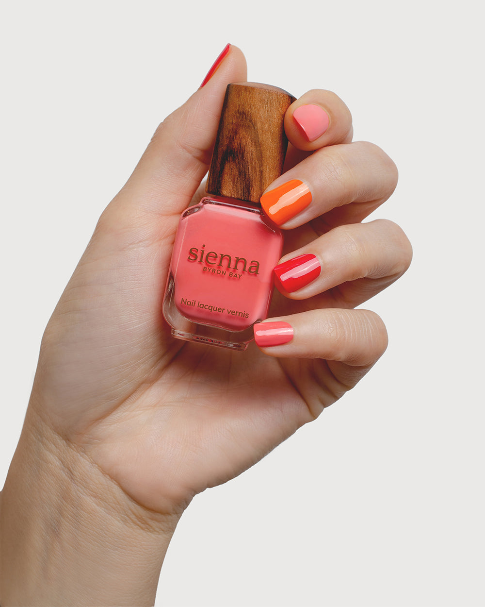 bright pink and orange nail polish hand swatch on fair skin tone by sienna byron bay