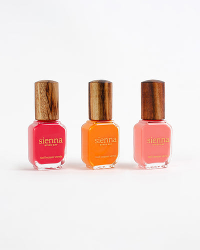 three bright summer colour nail polish bottles with a timber cap