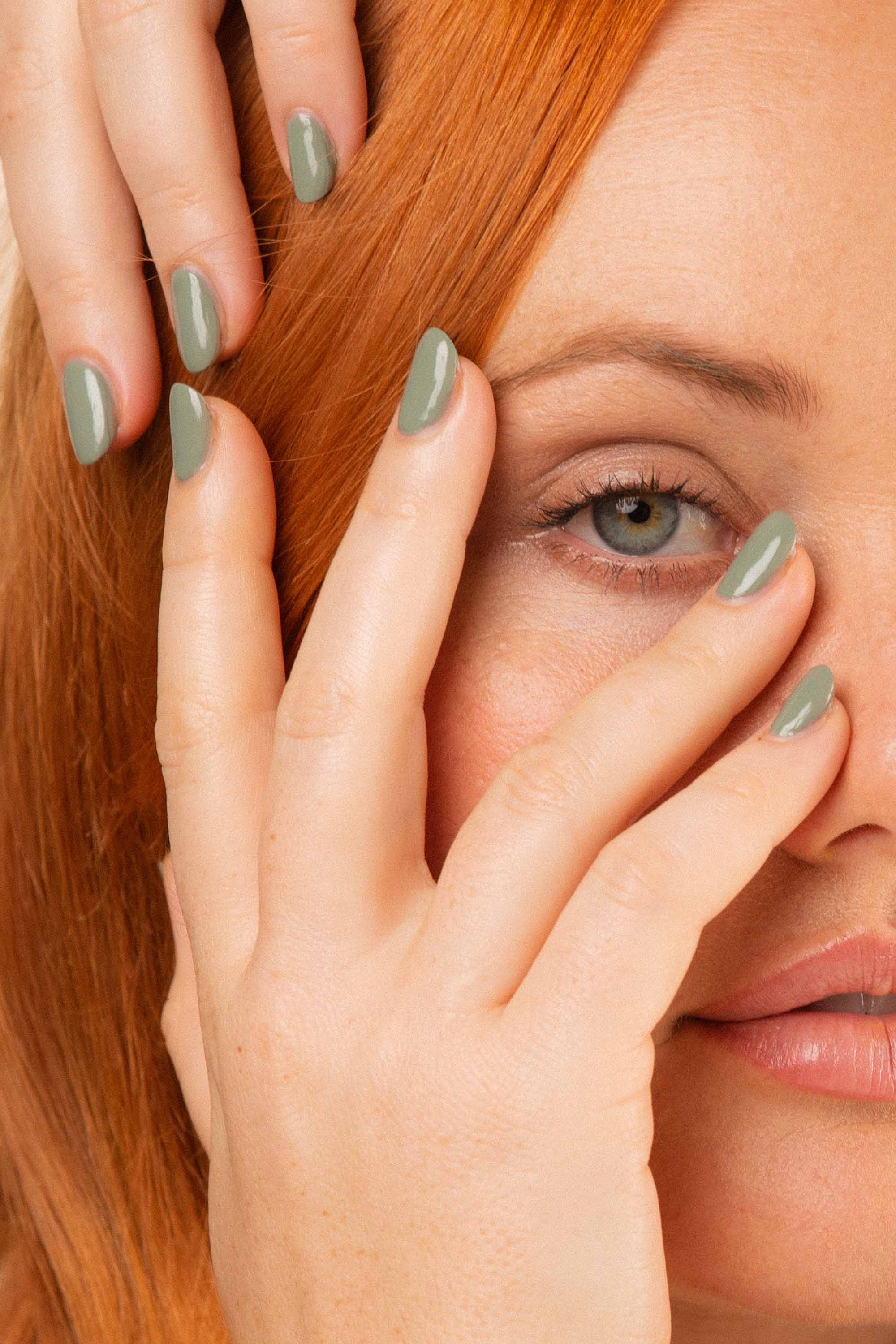 Fair skin woman with auburn red hair wearing Soundscape sage green nail polish by Sienna Byron Bay