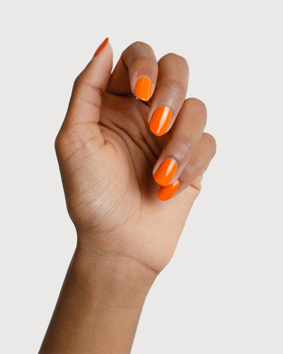 bright orange nail polish swatch on medium skin tone by sienna