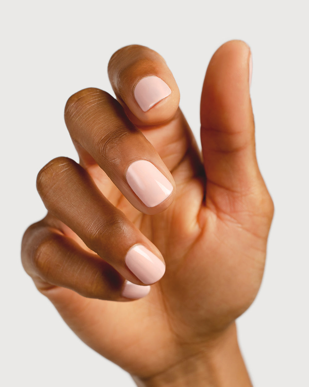 pastel pink nail polish hand swatch on medium skin tone