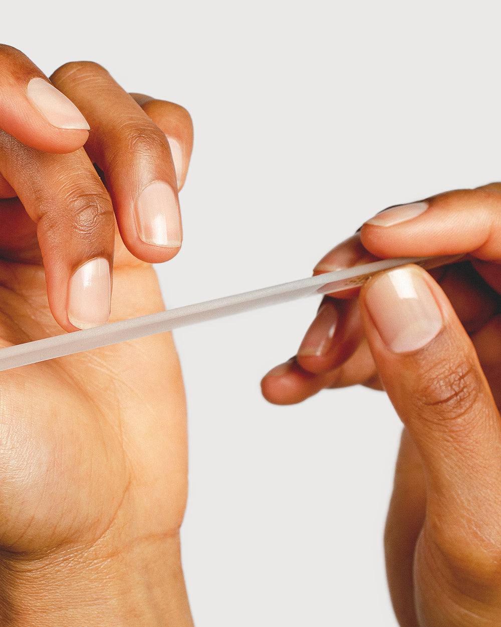 person filing nails with a glass nail file up close