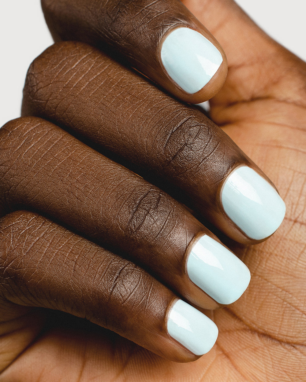 Pastel blue nail polish hand swatch on dark skin tone