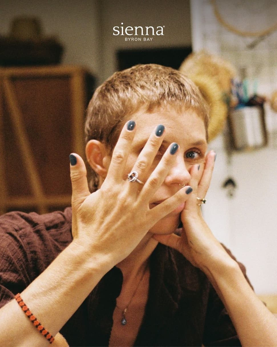 Woman in a home kitchen covering her face with her hands.