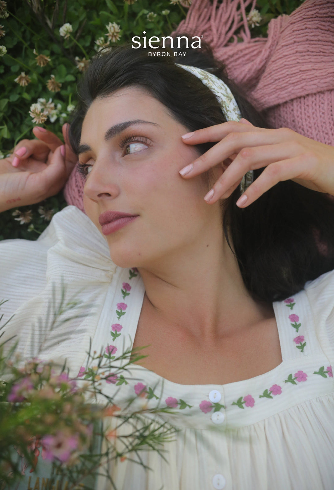 A woman in clover showcasing a shimmering nude-pink manicure by Sienna Byron Bay.