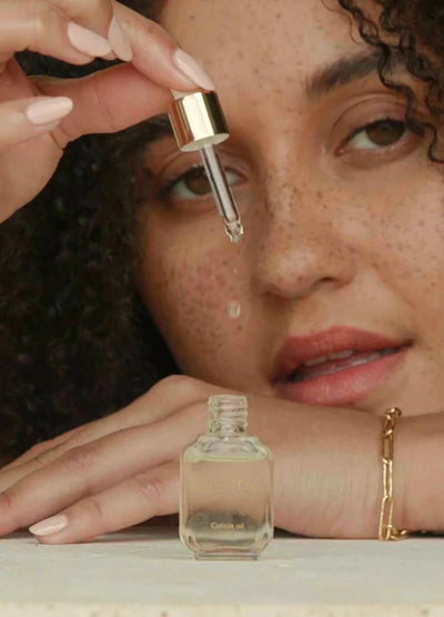 WOman with freckles dropping cuticle oil into glass bottle by Sienna Byron Bay