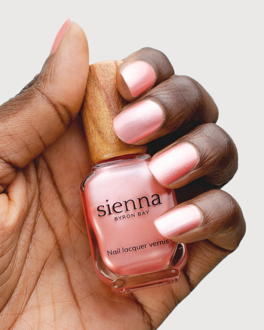 Warm Pink Satin Nail Polish on Dark Skin Tone with Glass Bottle Close Up