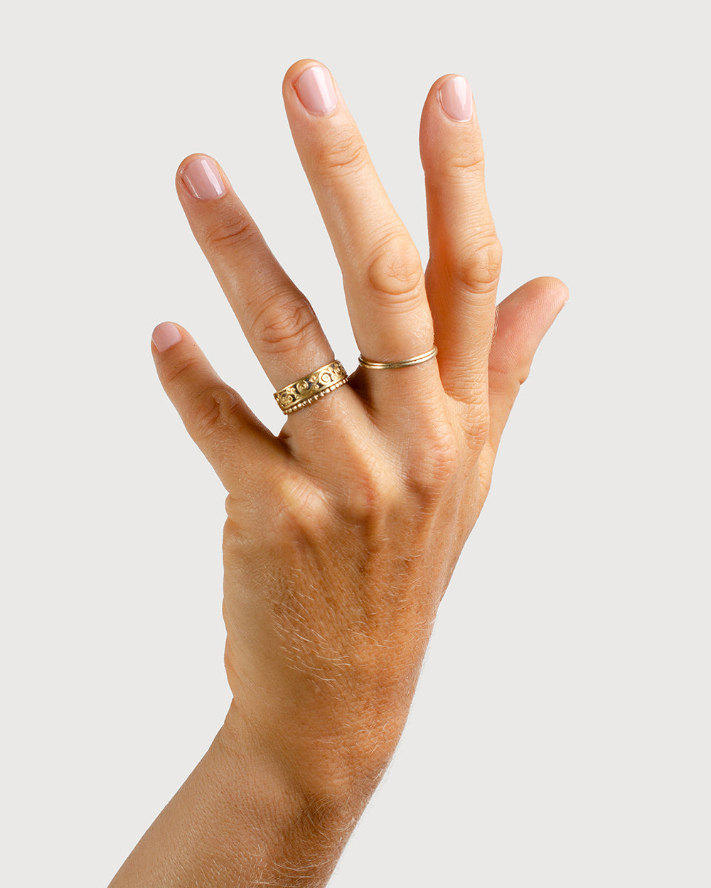 Fair skin tone hand with Amour soft pink crème nail colour and short, healthy natural nails and delicate gold jewellery