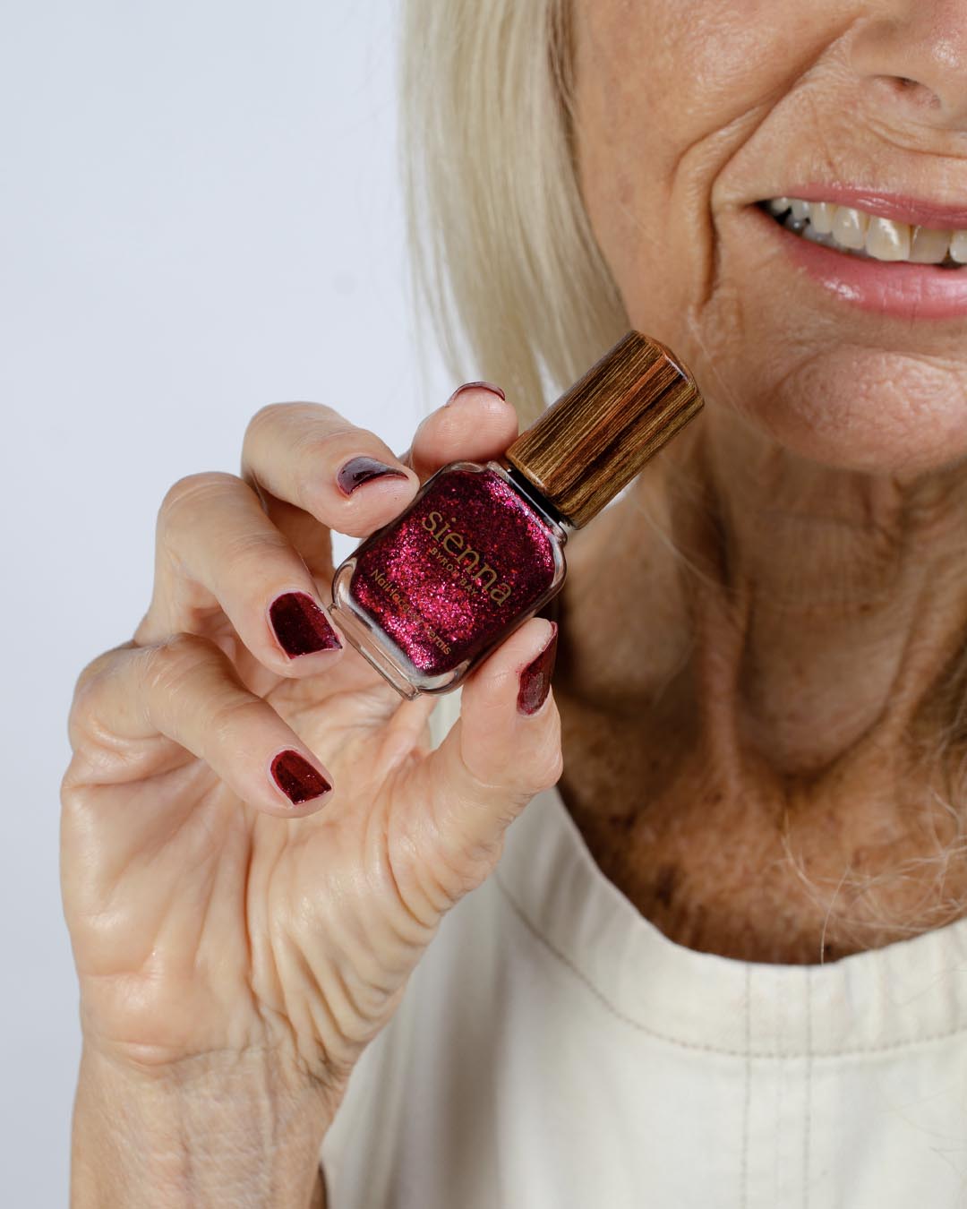 Fair skin tone hand holding Starlit Rose bottle with timber cap 