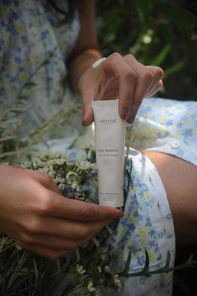Person holding a skincare product with a natural background