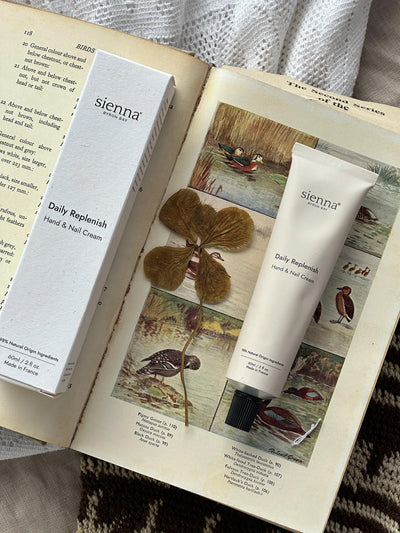 Sienna Daily Replenish Hand & Nail Cream with packaging on an open book