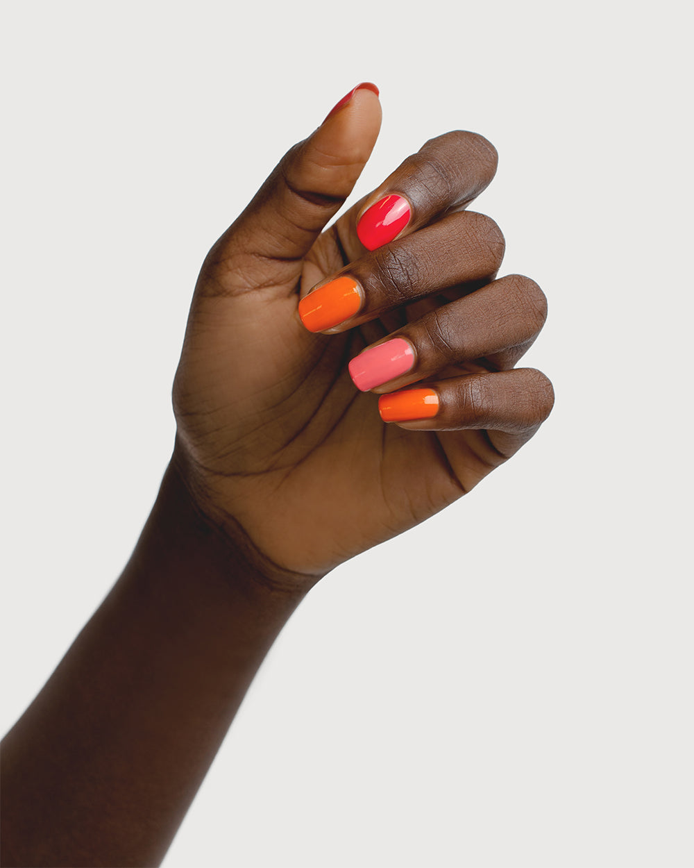 Bright pink and orange nail polish hand swatch on dark skin tone by sienna byron bay