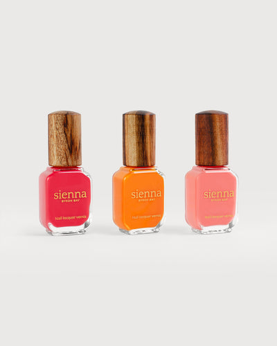 three bright summer colour nail polish bottles with a timber cap