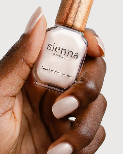 Warm Ivory Pearl Nail Polish Painted on Dark Skin Tone with Glass Bottle