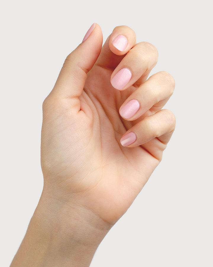 Fair skin tone hand with strong and healthy natural nails painted in shimmery Magic pink.