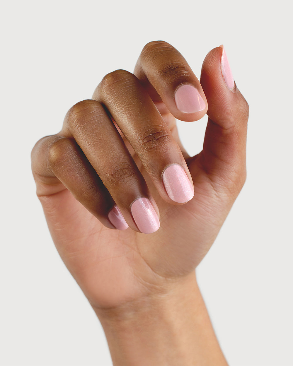 Medium skin tone hand with natural nails  painted in shimmery pink.