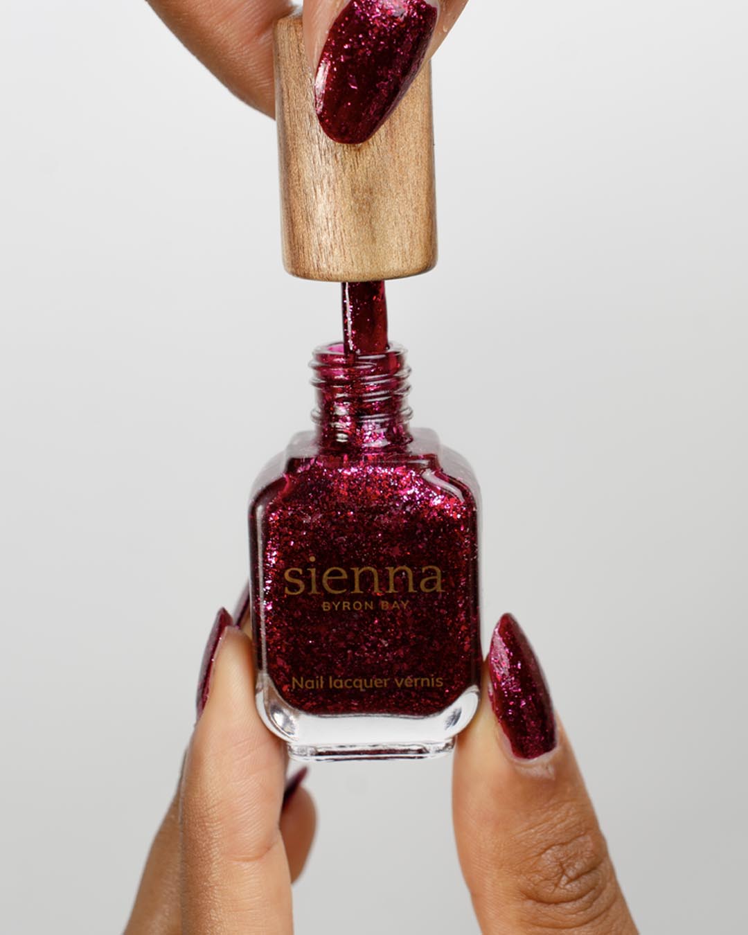 Medium skin tone hand holding Starlit Rose bottle close up 