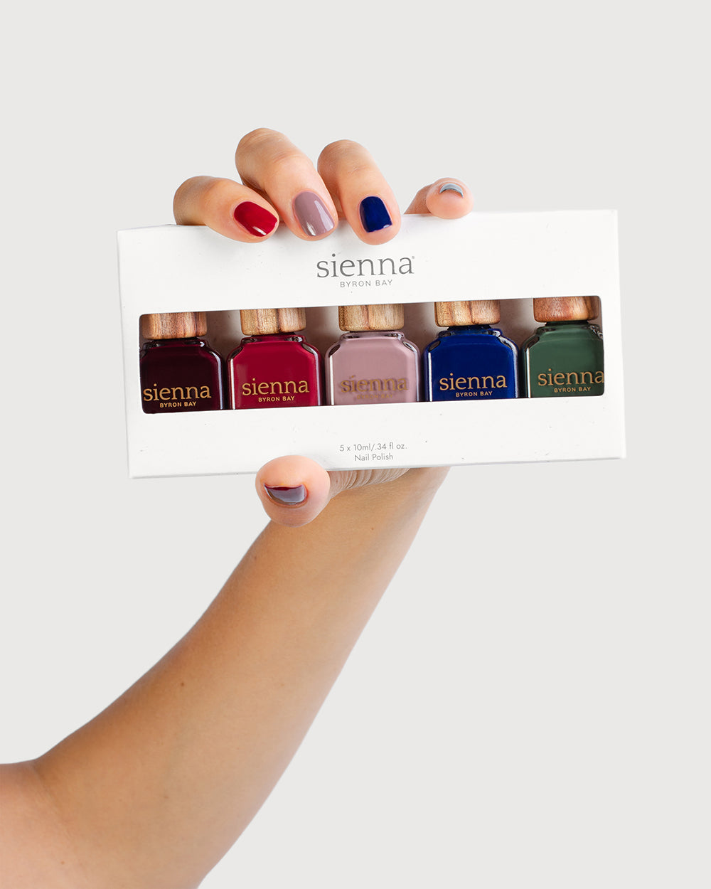 Fair Skin Tone hand holding the Midnight Shadows Quin Pack with painted nails