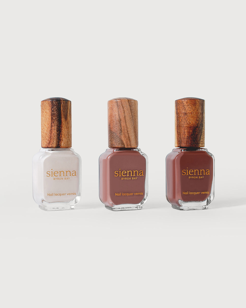 offwhite, mylk chocolate crème, and deep burnt amber nail polish bottles with timber caps