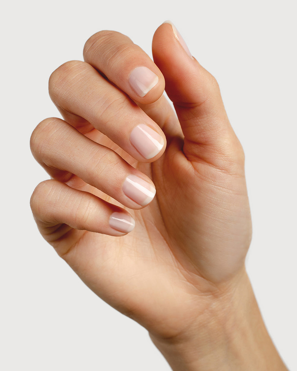 Fair skin tone hand wearing best selling colour Peace. Nails are strong, and healthy and painted in sheer Peace pink.
