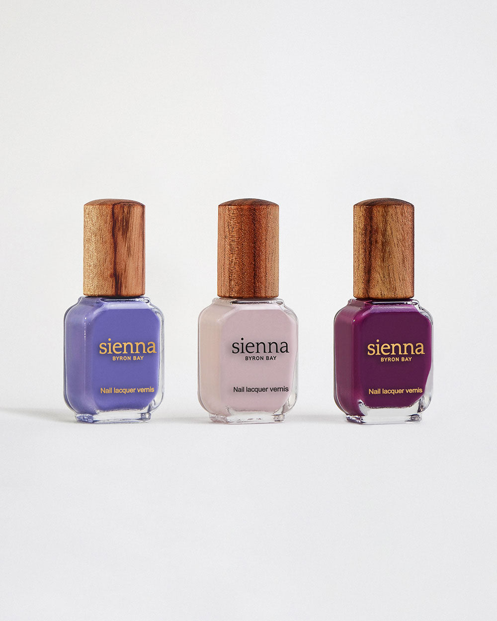 The Quiet Trio Gentle Midtone Blue Lilac Crème, Tranquility Light Mauve Rose Crème, Reverence Violet Grape Crème nail polish bottles with timber lid by Sienna Byron Bay.