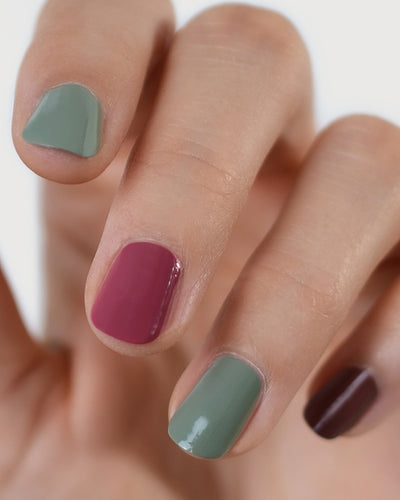 Fair skin hand wearing Soundscape sage green crème, Heartspace raspberry sorbet crème and Grounded mylk chocolate crème nail polish by Sienna.