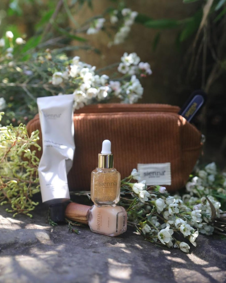 Cosmetic bag with skincare products and flowers on a stone surface