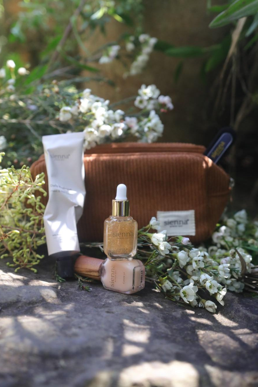 Cosmetic bag with skincare products on a stone surface with flowers in the background