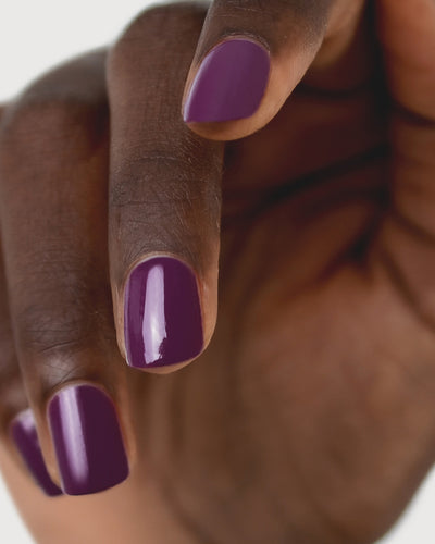 Reverence Violet Grape Crème nail polish by Sienna Byron Bay on dark skin tone hand.