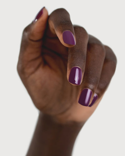 Reverence Violet Grape Crème nail polish by Sienna Byron Bay on dark skin tone hand.