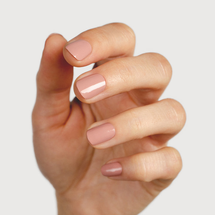 Fair skin tone hand with natural nails painted in Rosie pink by Sienna Byron Bay. Nails are strong, and healthy and painted in crème glaze Rosie pink.