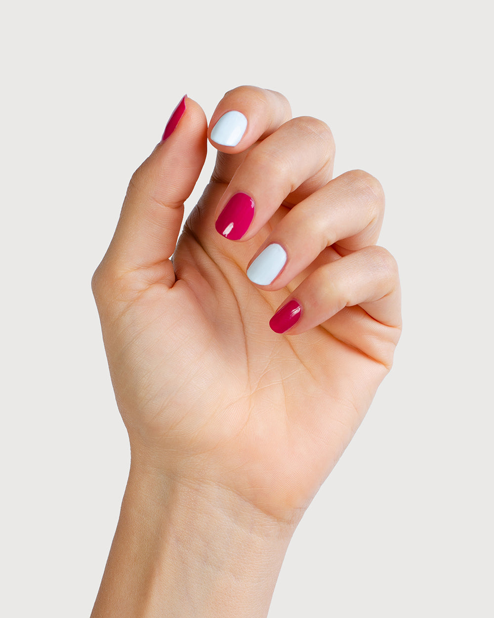 Pastel blue and fuschia pink nail polish on fair skin tone