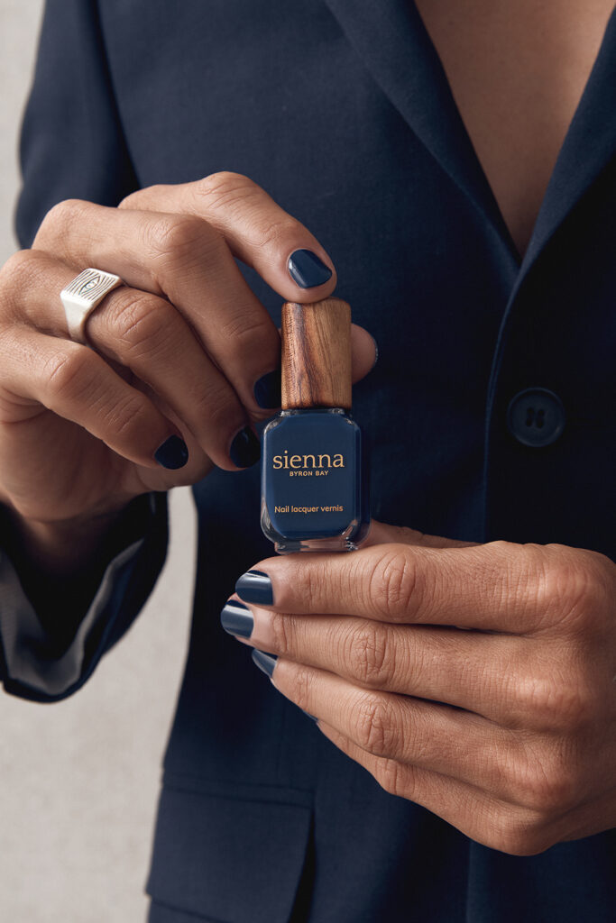 man wearing and holding navy blue nail polish by sienna