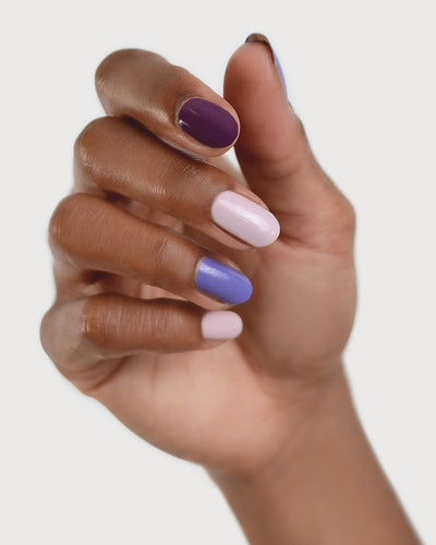Medium skin hand tone wearing The Quiet Trio Gentle Blue Lilac Crème, Tranquility Light Mauve Rose Crème and Reverence Purple Grape Creme Nail polish.