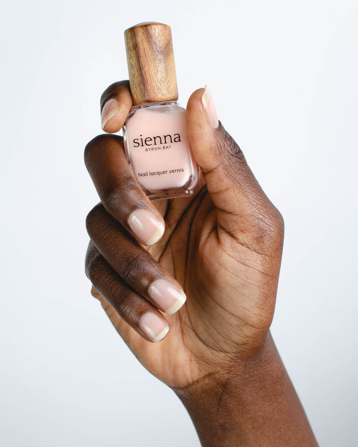 Dark skin tone hand holding Smooth Base Ridge Filler bottle with timber cap