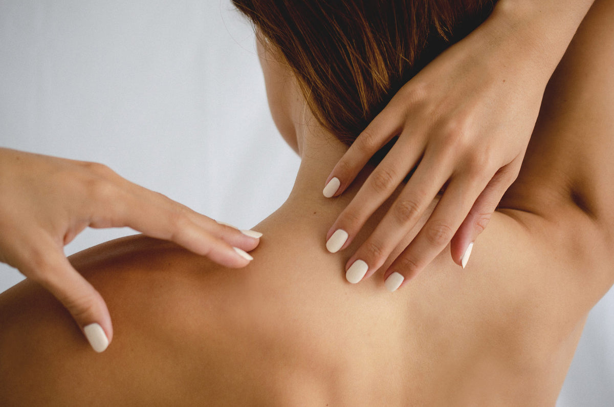 Tan skin woman wearing Luna eggshell white clean nail polish by Sienna Byron Bay placing hands on back 