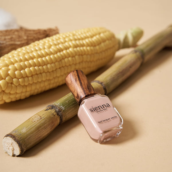 light pink nail polish resting on sugar cane with corn and cassava in the background by sienna