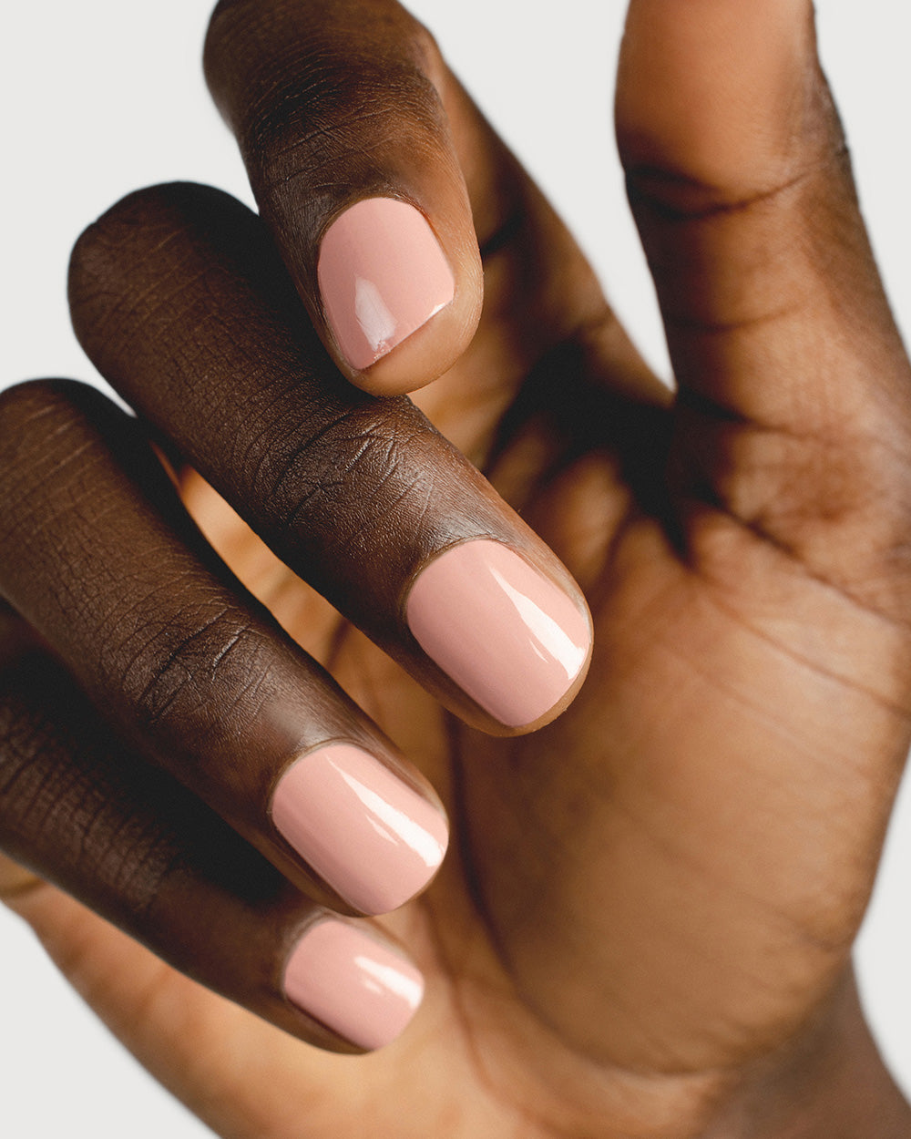 Dark skin tone hand wearing earthy crème pink colour Rosie. Nails are strong, and healthy and painted in crème glaze Rosie pink.
