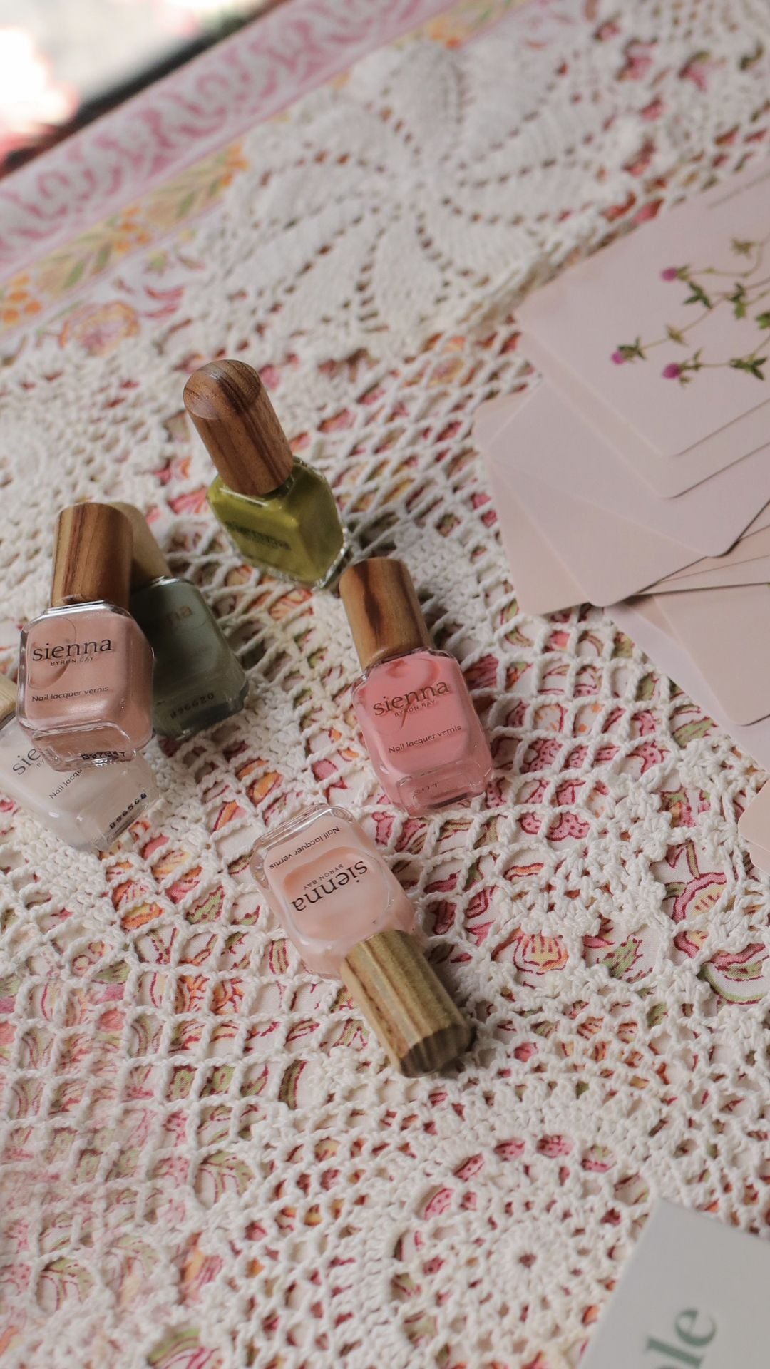 Set of nail polish bottles on a floral fabric background