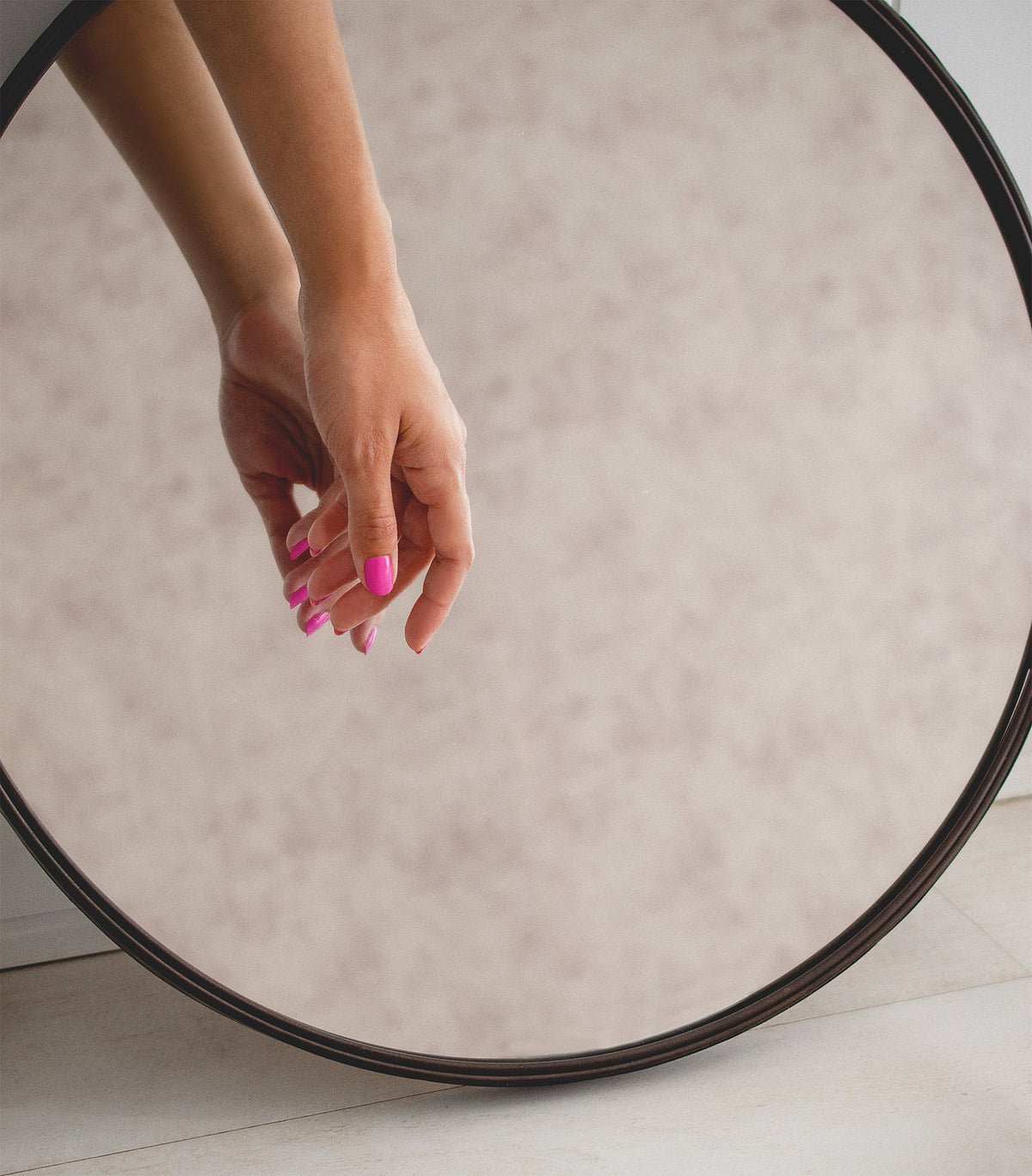 Woman with fair skin wearing Spell non-toxic nail polish by Sienna Byron Bay holding hand to mirror.