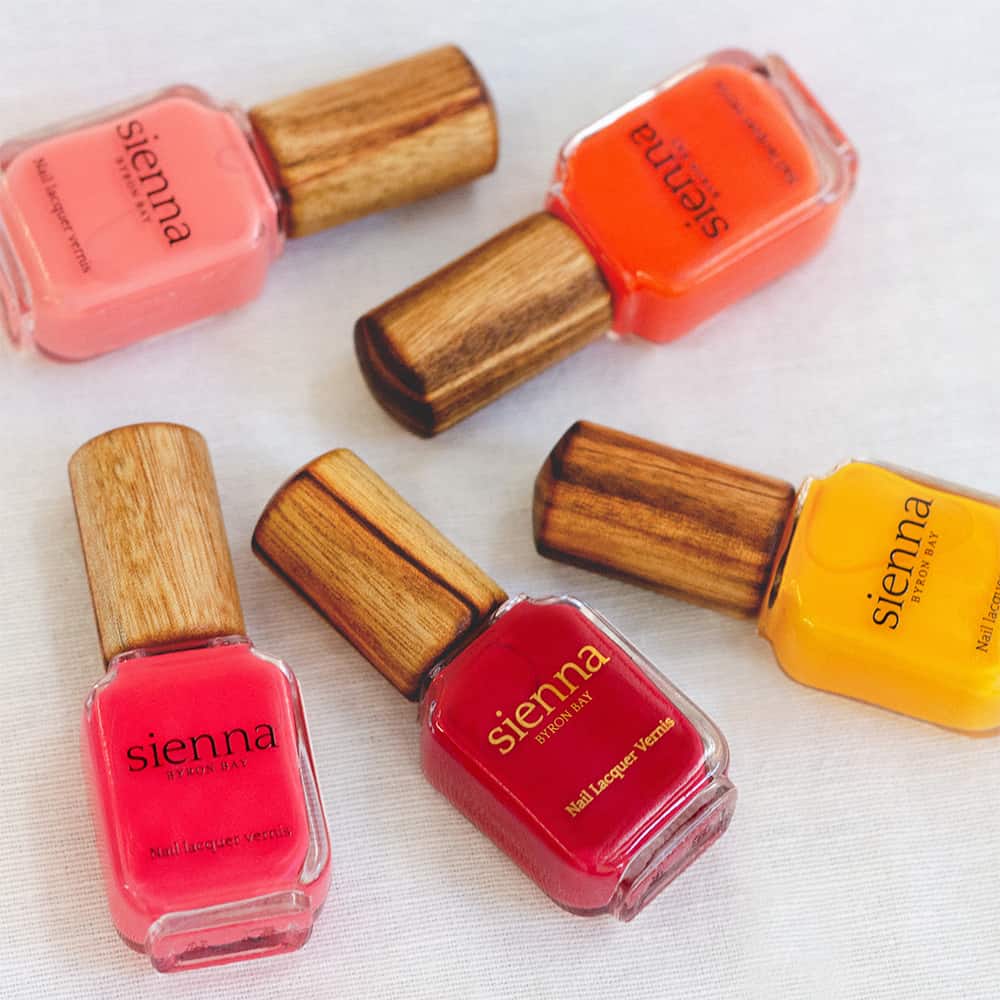 bright pink orange red and yellow nail polish in glass bottle with timber cap by sienna