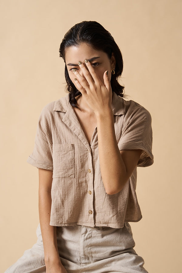 young woman wearing beige clothes and green nail polish by sienna
