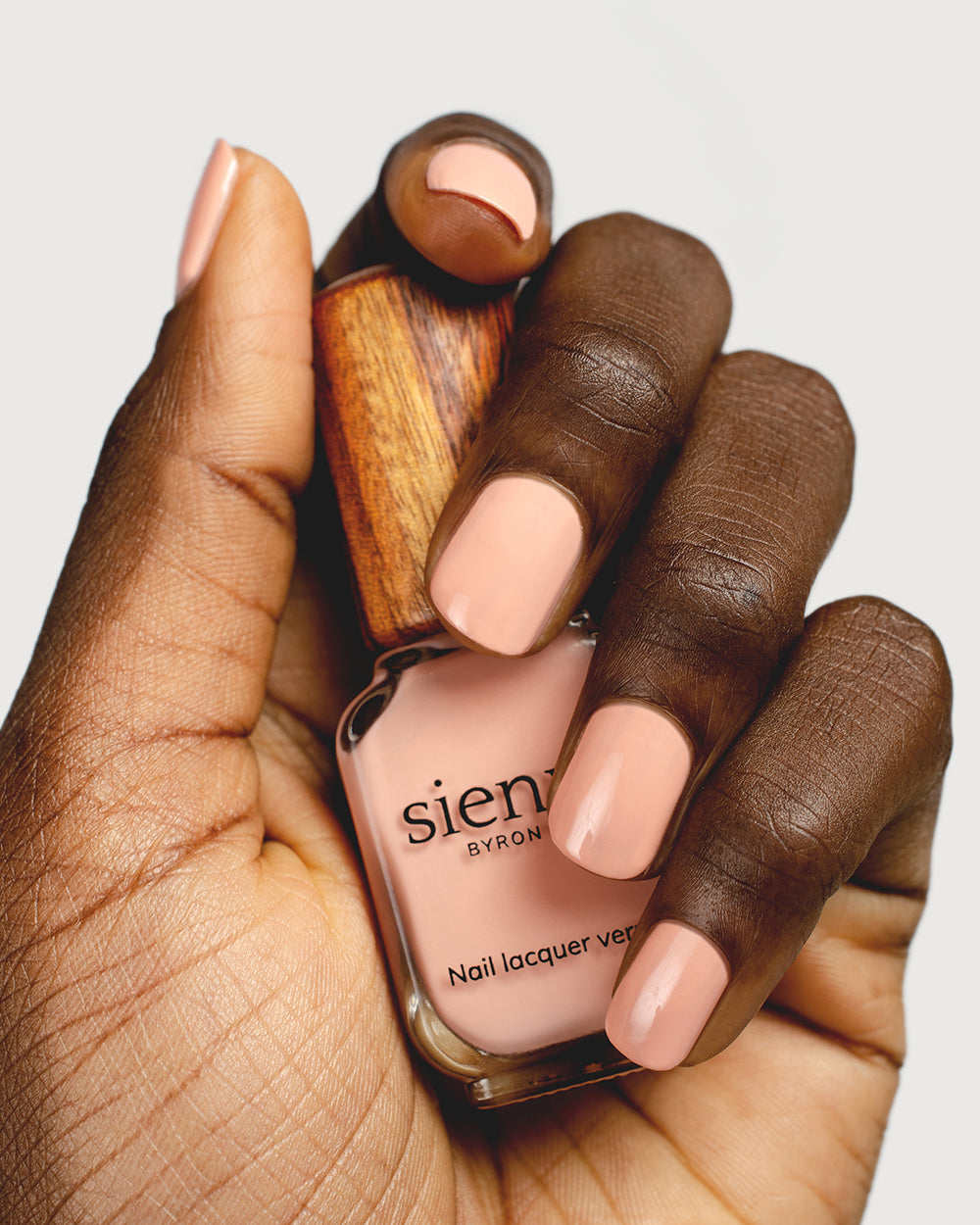 nude pink nail polish hand swatch on dark skin tone holding a sienna bottle