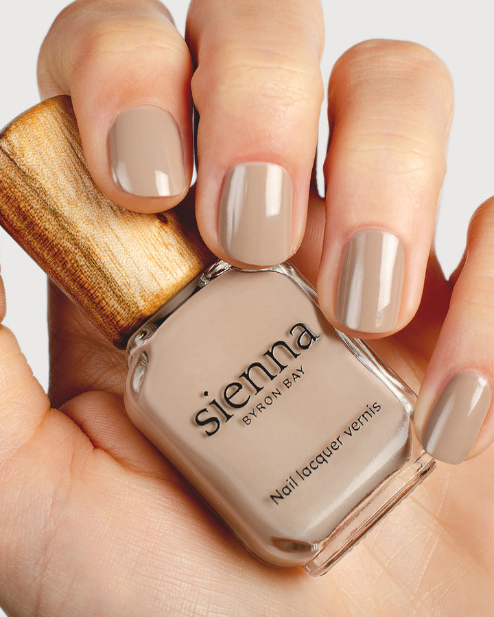 Warm clay nail polish hand swatch on fair skin tone holding a sienna bottle