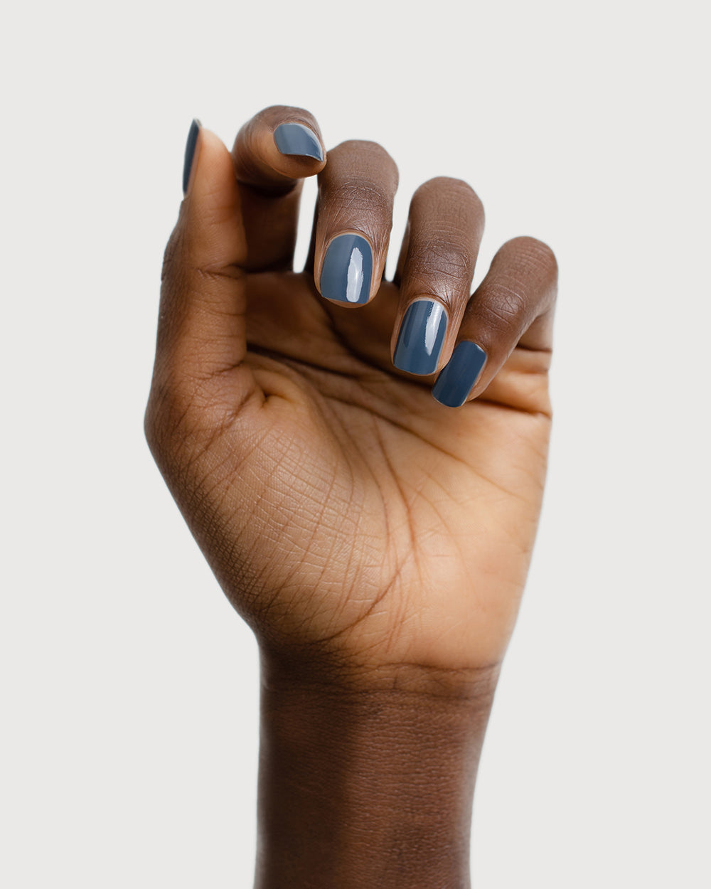 Dark granite blue-grey nail polish hand swatch on dark skin tone