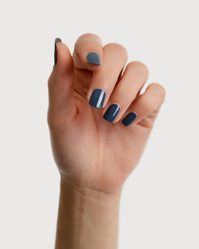 Dark granite blue-grey nail polish hand swatch on fair skin tone
