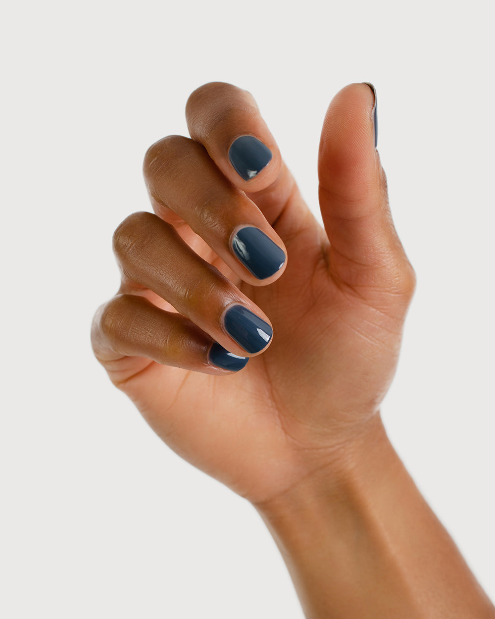 Dark granite blue-grey nail polish hand swatch on medium skin tone