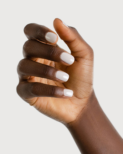 Light cool-grey nail polish hand swatch on dark skin tone