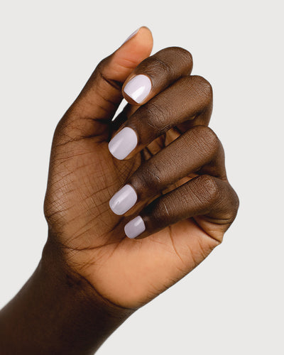 Pastel purple-grey nail polish hand swatch on dark skin tone